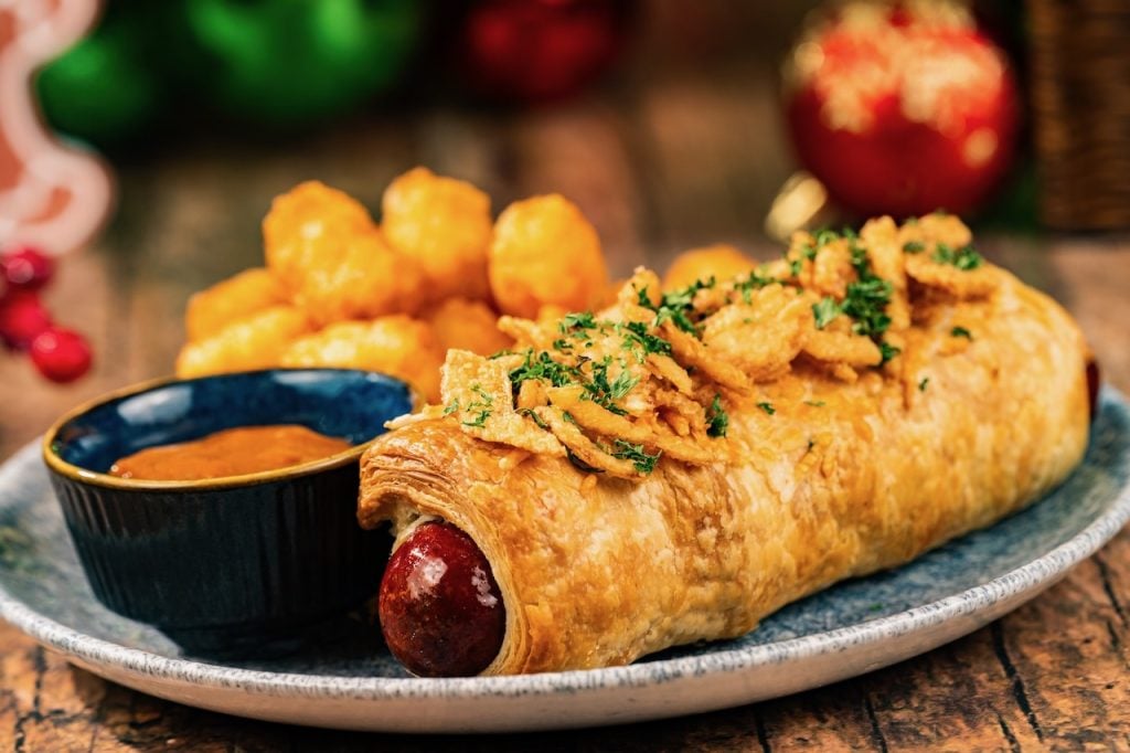 2026-WDW-MVMCP-Foodie-Guide-PigInABlanket | WDWINFO.COM The 2026 Mickey’s Very Merry Christmas Party Foodie Guide is HERE! 2026-WDW-MVMCP-Foodie-Guide-PigInABlanket