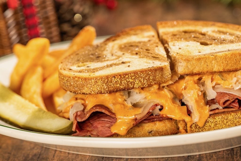 2026-WDW-MVMCP-Foodie-Guide-ReubenSandwich | WDWINFO.COM The 2026 Mickey’s Very Merry Christmas Party Foodie Guide is HERE! 2026-WDW-MVMCP-Foodie-Guide-ReubenSandwich